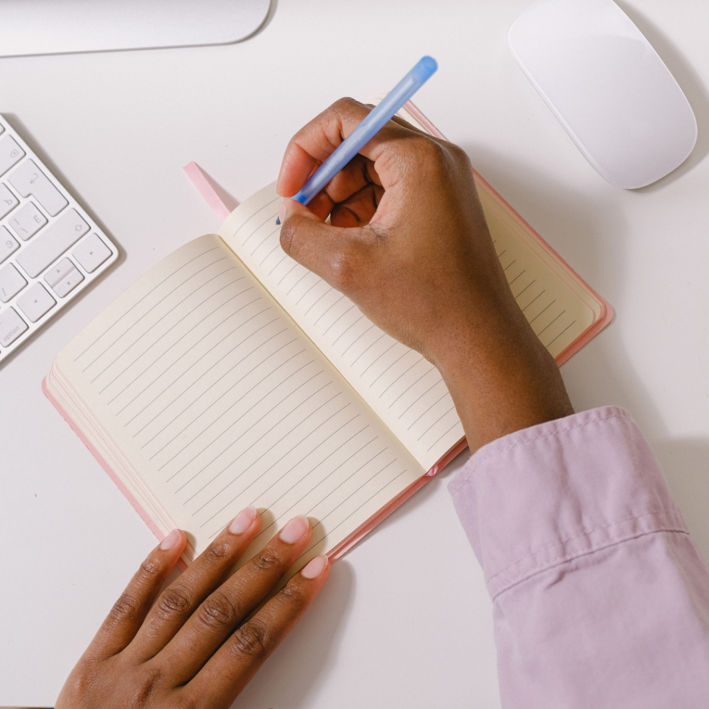 Black woman writing daily affirmations in journal