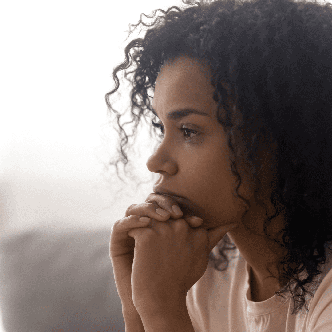 Up close image of Black woman, sitting and thinking head resting on her hands. How to forgive yourself.