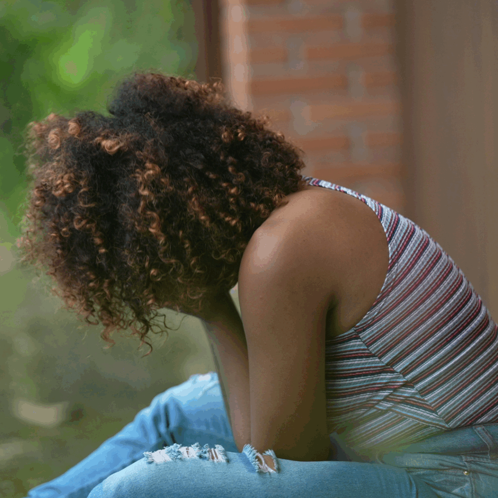 Black woman sitting outside, hand in face, struggling with how to heal from childhood trauma