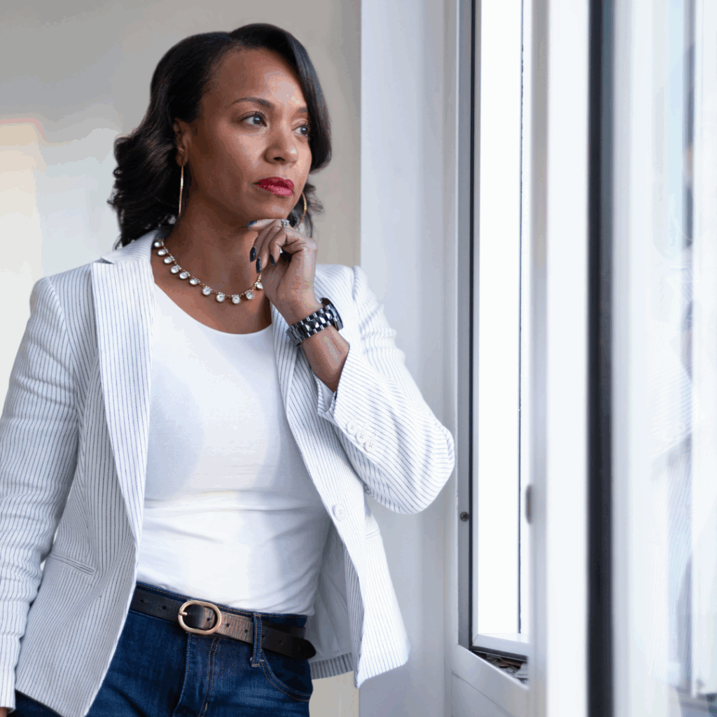 Black woman professional staring out of the window wondering how to overcome fear of failure