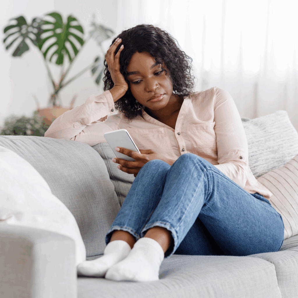 Black woman sitting on sofa scrolling through her phone | trust issues