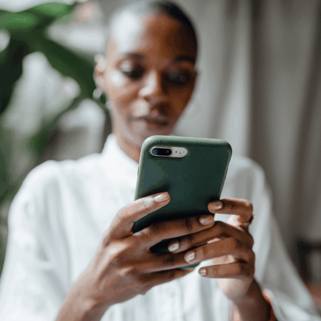 Black woman slightly smiling looking on her phone | apps for anxiety