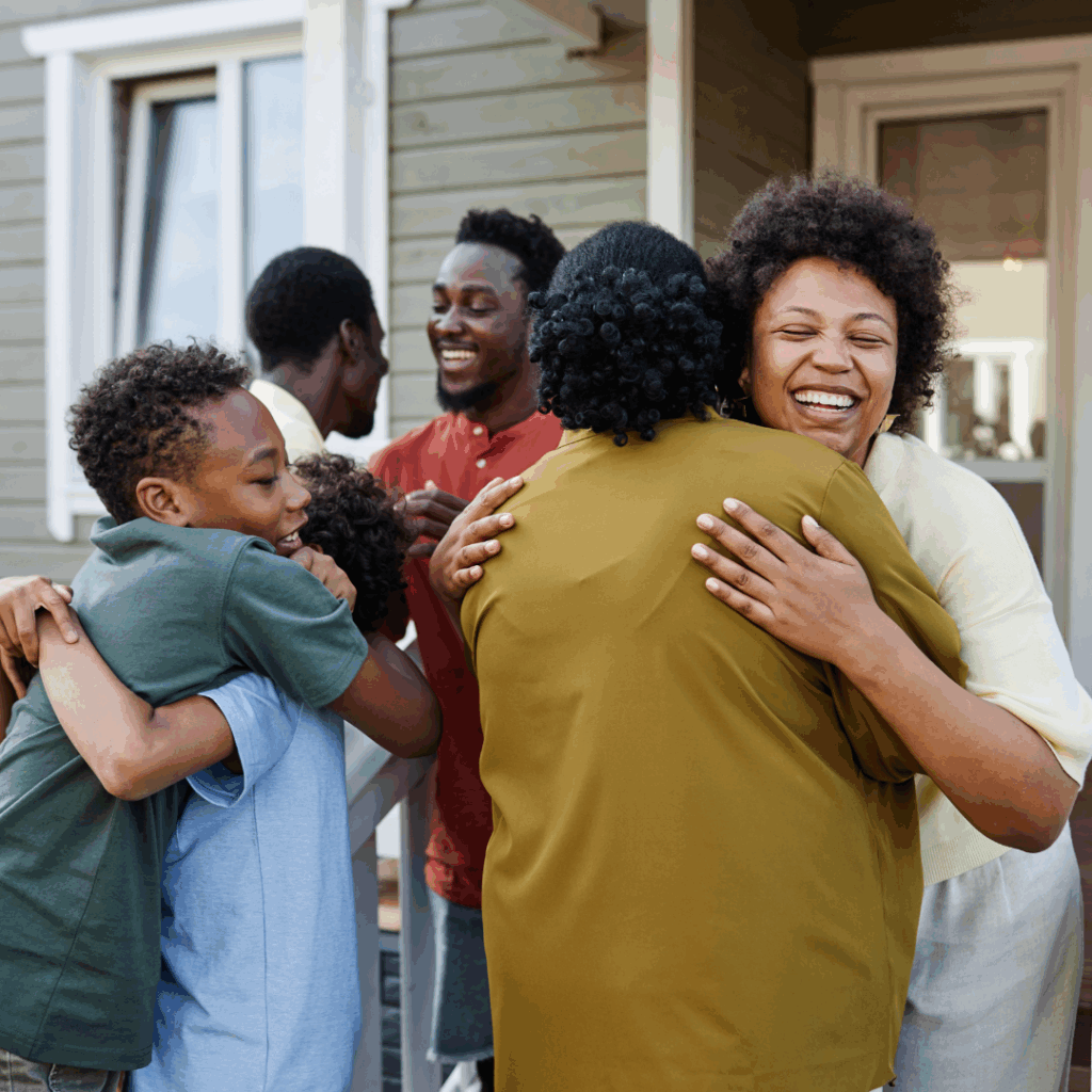 Black family greeting each other hugs at the entrance of a house | How to set boundaries with family
