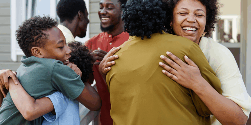 Black family greeting each other hugs at the entrance of a house | How to set boundaries with family