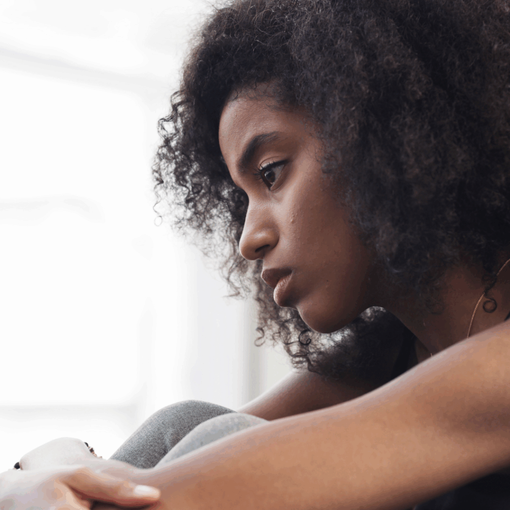 Black woman looking sad, arms hugging needs 
 How to help a friend with depression