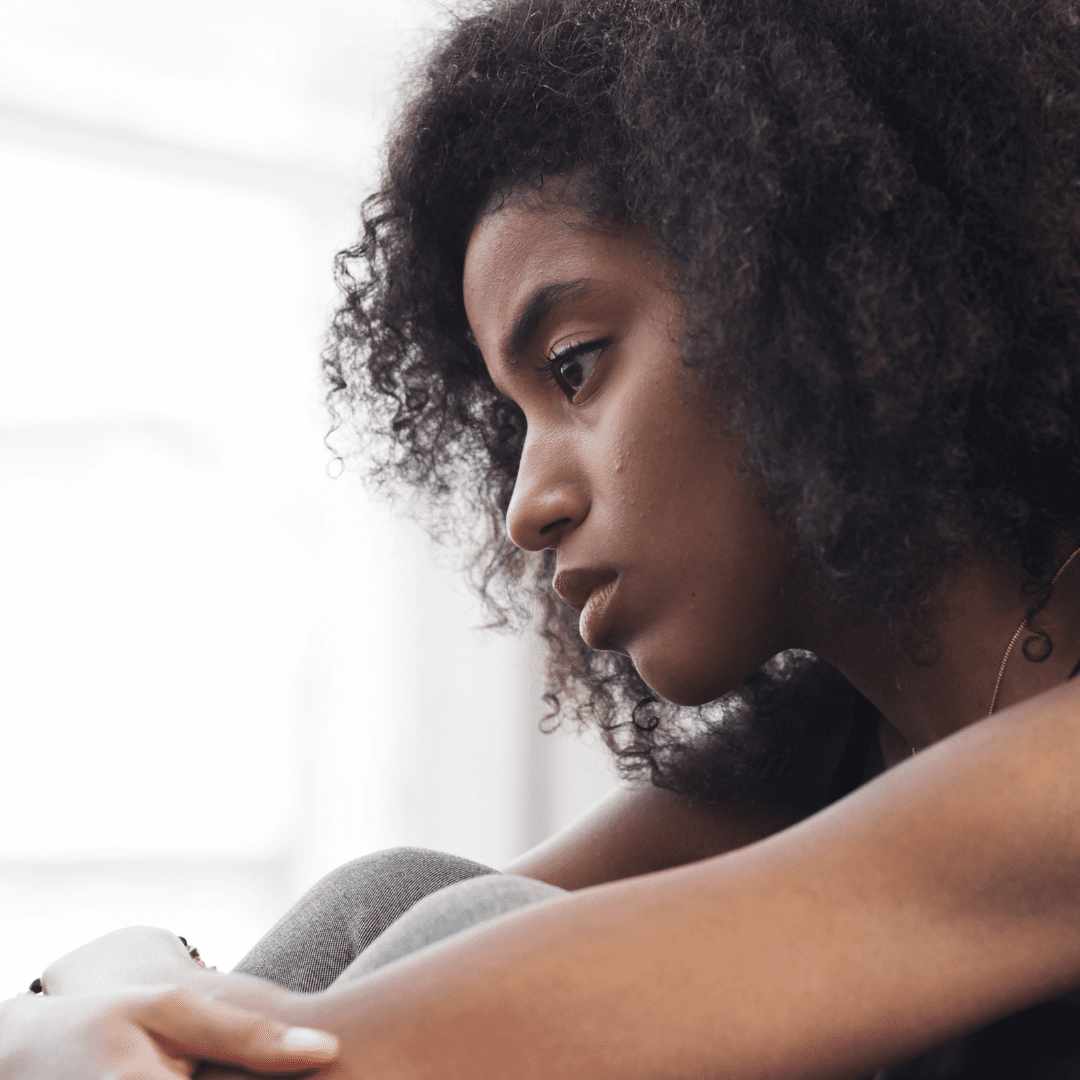 Black woman looking sad, arms hugging needs How to help a friend with depression