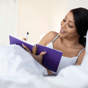 Black woman lying in bed writing in general | mental health goals for Black women