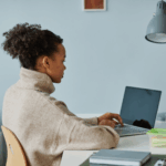 Black woman sitting at desk typing on laptop | How to respond to job search depression