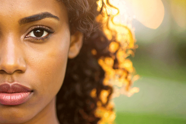 Young Black woman up close, outdoors with sun shining behind her | Why you can stop judging your emotions
