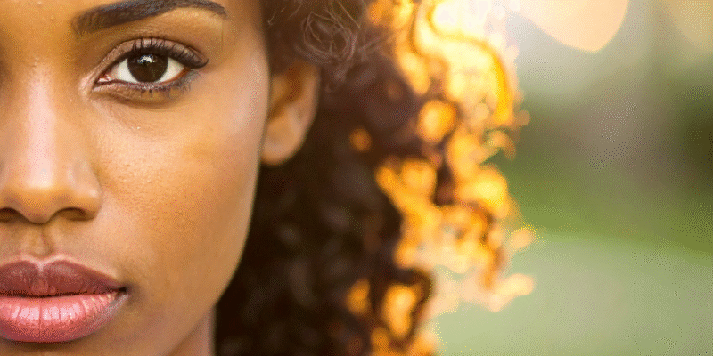 Young Black woman up close, outdoors with sun shining behind her | Why you can stop judging your emotions