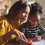 Black mother helping daughter with art project at the table } Emotionally drained