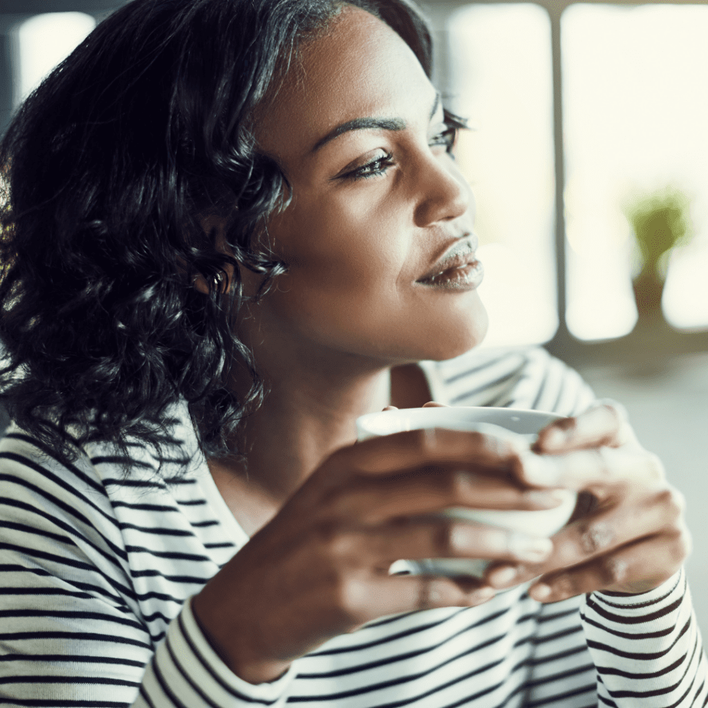 Black woman holding coffee and looking out of window | When to seek mental health support