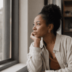 Black woman looking out of the window thinking | coaching vs counseling vs therapy