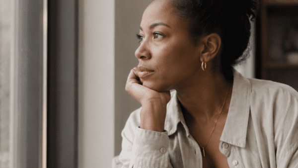 Black woman looking out of the window thinking | coaching vs counseling vs therapy